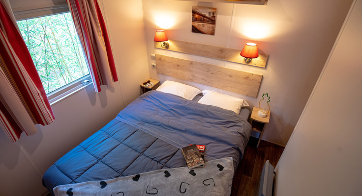 Chambre avec lit double des locations de vacances roulottes en bois au camping la Grainetière